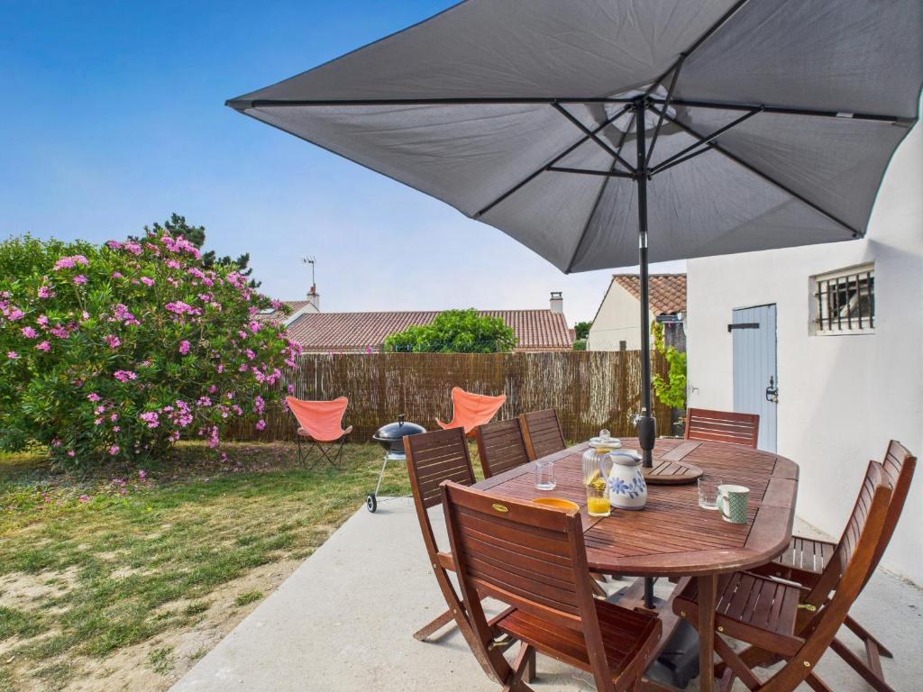 a wooden table with an umbrella on a patio at Maison pour 6 avec jardin proche du centre in Saint-Gilles-Croix-de-Vie