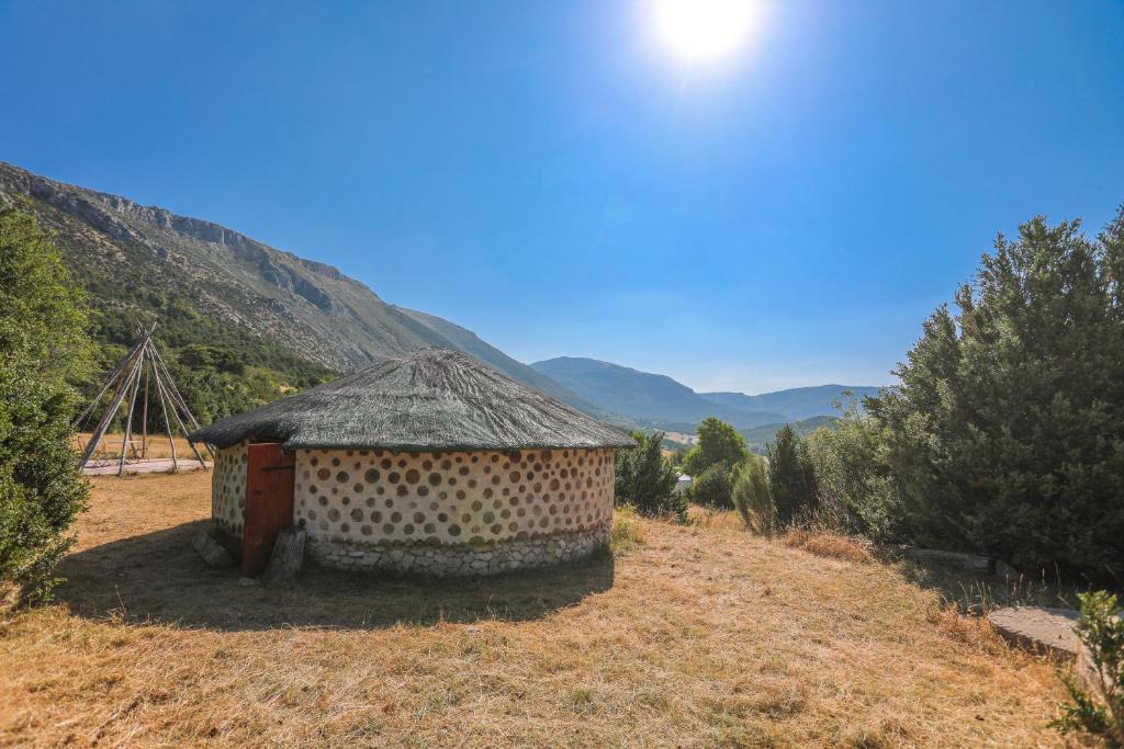 une cabane dans un champ avec des montagnes en arrière-plan dans l'établissement Case Africaine, à Bargème