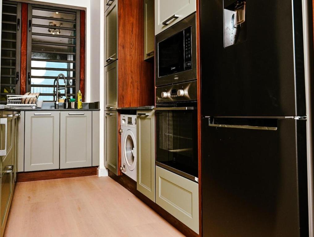 Una cocina con electrodomésticos negros y lavadora y secadora. en Apartment in flic en Flac, en Flic en Flac