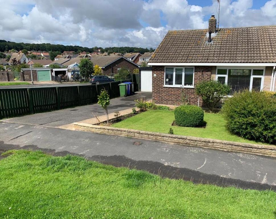 a house with a fence and a yard at Sands Lane Retreat - Cozy Bungalow in Hunmanby in Filey