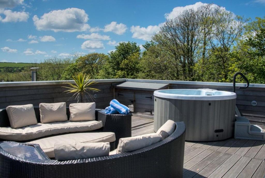 a deck with a hot tub and wicker chairs and a hot tub at House 2 in Looe