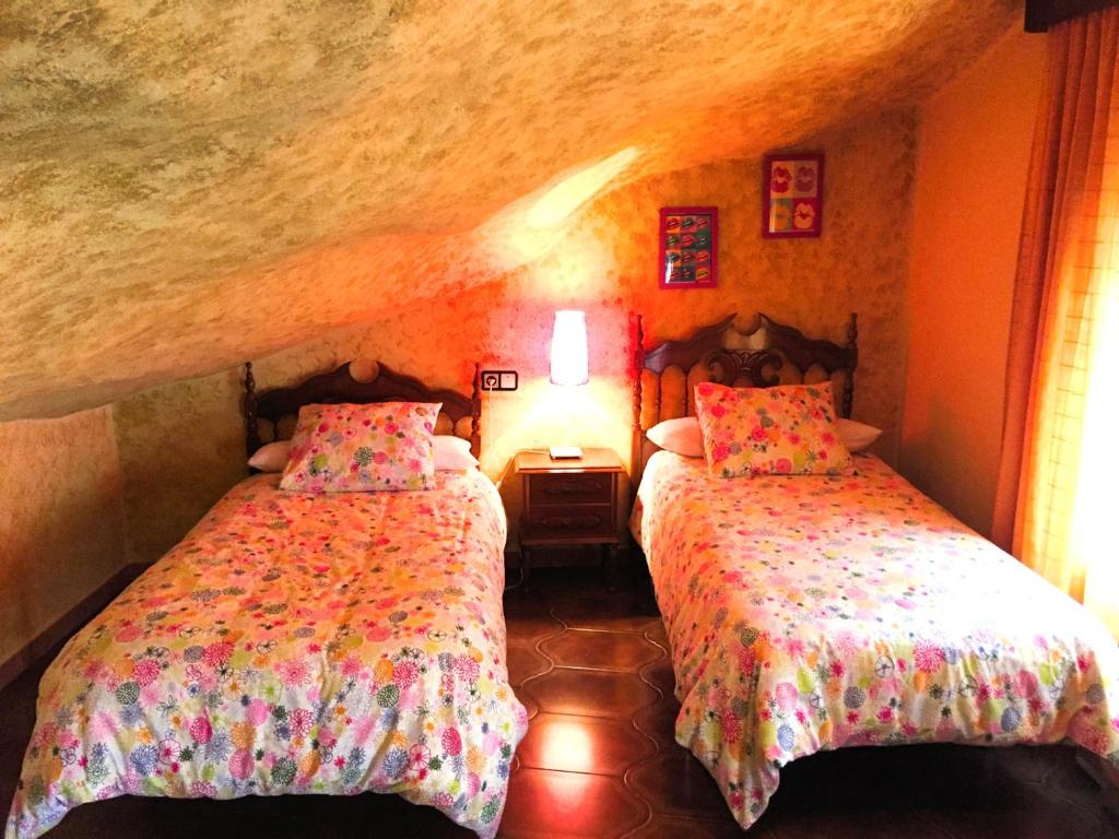 1 dormitorio con 2 camas en una habitación de piedra en Casa Rural Cuevas del Sol, en Setenil