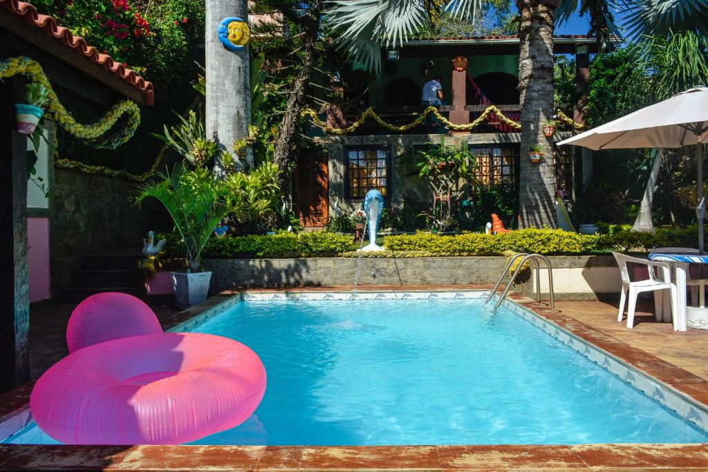 een zwembad met een stoel en een parasol bij Suítes Casa do Barão in Búzios