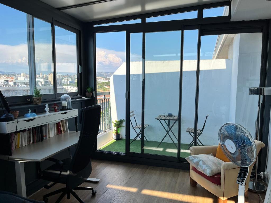 un bureau avec un bureau et une chaise et de grandes fenêtres dans l'établissement Charmant type 2 au cœur de la ville, à Marseille