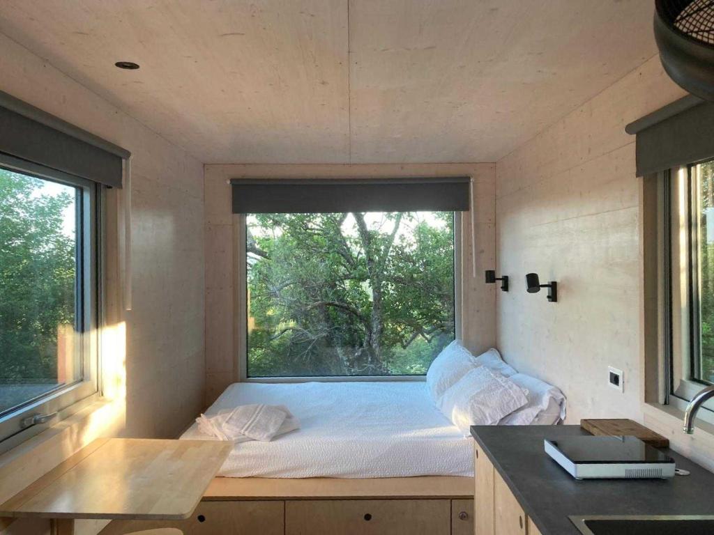 a bed in a small room with a large window at Una Stanza con vista tra le colline senesi - Friland in Fattoria Falsini