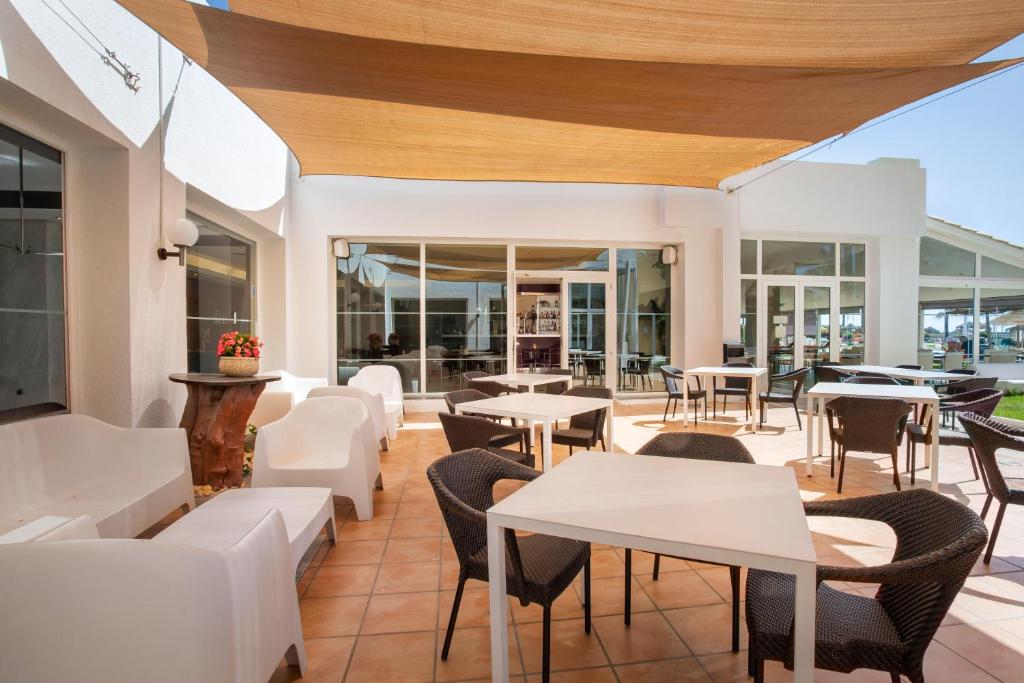 a restaurant with white tables and chairs and windows at Sol Guadalmar in Málaga