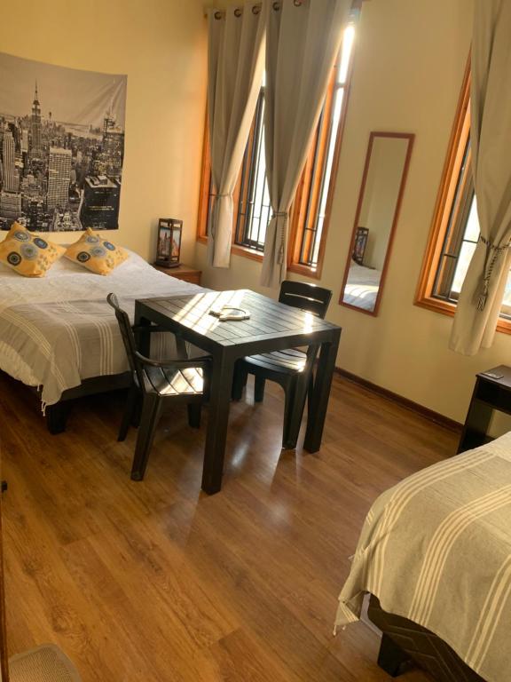 a bedroom with two beds and a table and chairs at Valparaíso Plan, cercano al Congreso Nacional in Valparaíso