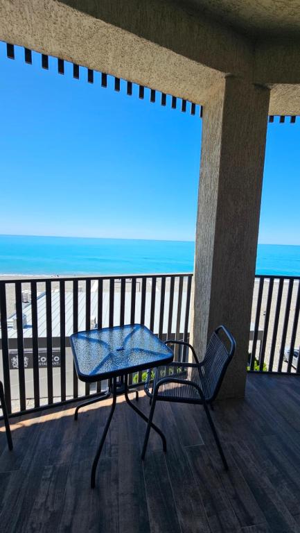 a table and a chair on a balcony with the beach at Bristol in Kvariati