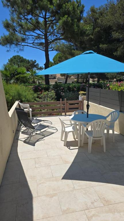 une table et des chaises avec un parapluie bleu dans l'établissement Naturiste Cap d'Agde Villa Héliovillage 33, au Cap d'Agde