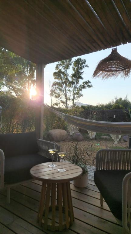 - une table et des chaises sur une terrasse en bois offrant une vue sur le coucher du soleil dans l'établissement Casa Figarella, à Calenzana