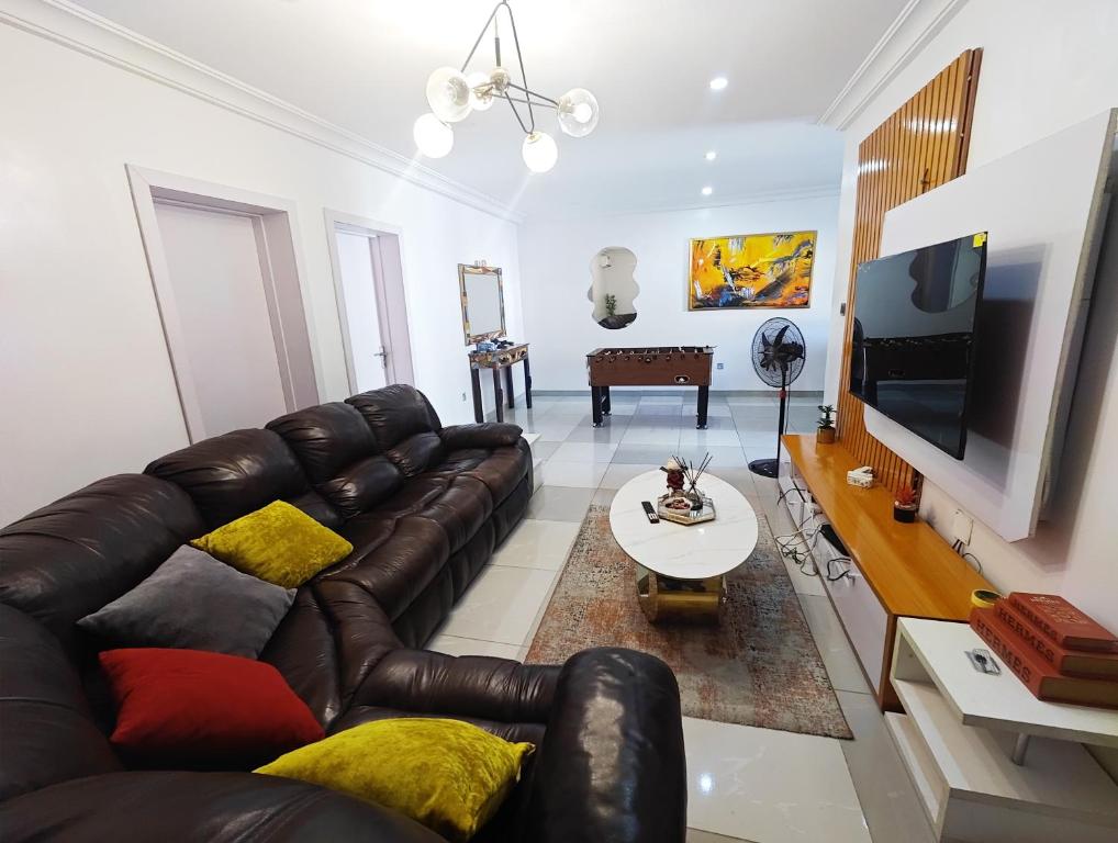 a living room with a leather couch and a tv at AB Luxury 2 bedroom Apartment with 24hr Electricity, Wifi, Fully Equipped Kitchen in Lagos