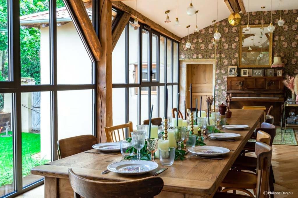 a long wooden table in a room with windows at Country Villa With Indoor Pool In Beaujolais in Romanèche-Thorins