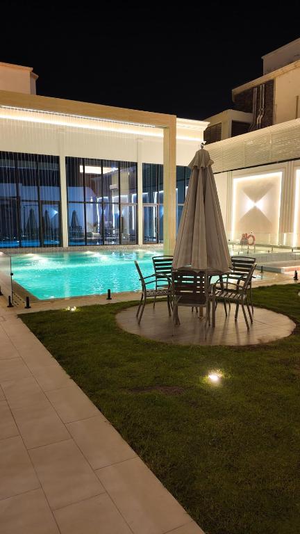 a table with an umbrella next to a pool at night at فرساي VERSAiLLES in Jeddah