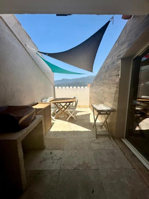 un patio avec une table, des chaises et un parasol dans l'établissement Appartement centre ville, à Propriano