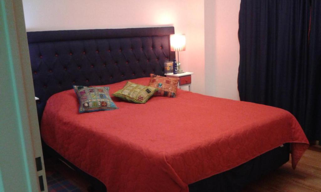 1 dormitorio con 1 cama roja y 2 almohadas en Avenida Cabildo 1535 en Buenos Aires
