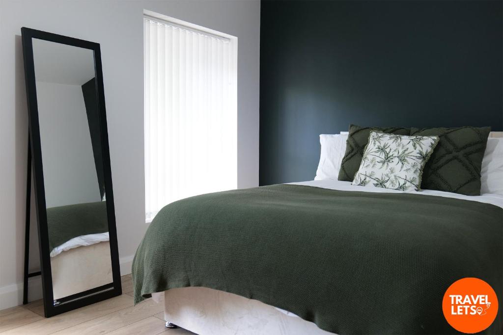 1 dormitorio con cama verde y espejo en Brooke Park House, en Londonderry County Borough
