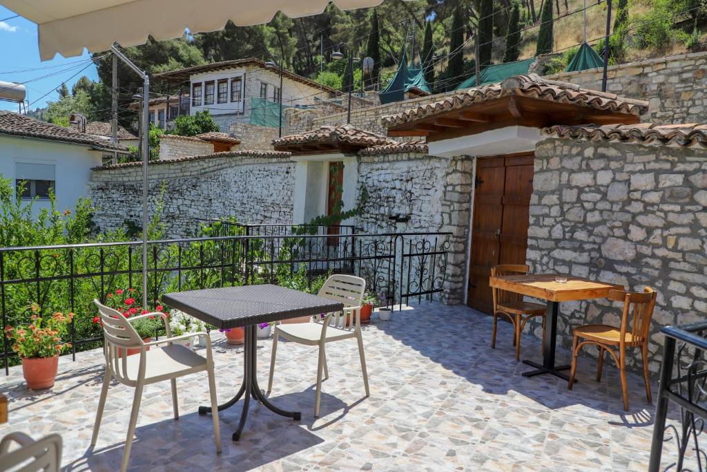 a patio with tables and chairs and a house at Vila Vreko in Berat