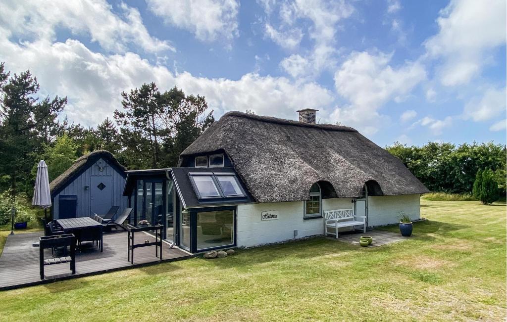 a house with a thatched roof with a deck at Hobbit Huset in Ringkøbing