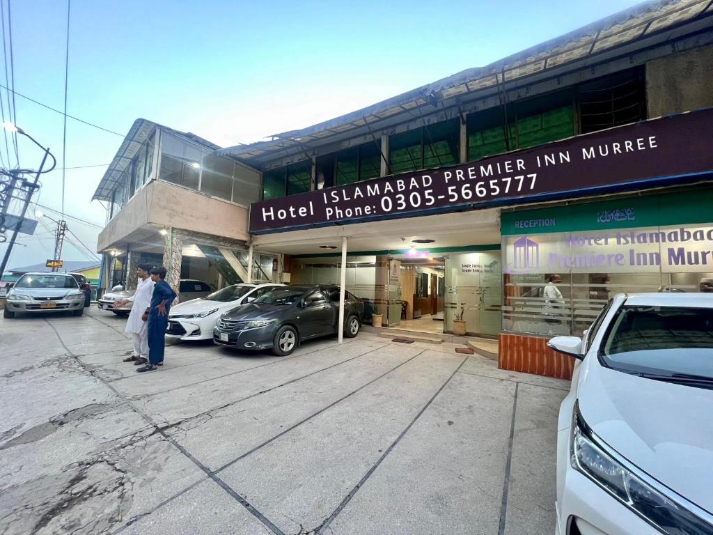 a man standing outside of a building with cars parked outside at Islamabad premier inn hotel murree in Murree