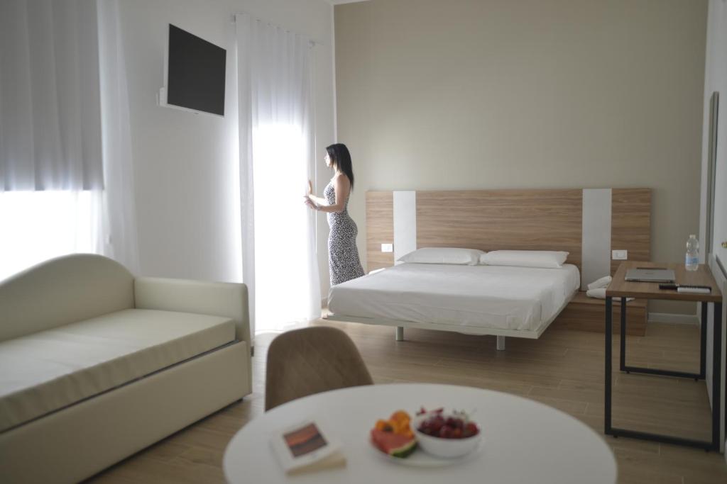 a woman standing in a bedroom looking out the window at HT Room Spa & Suite in Brindisi