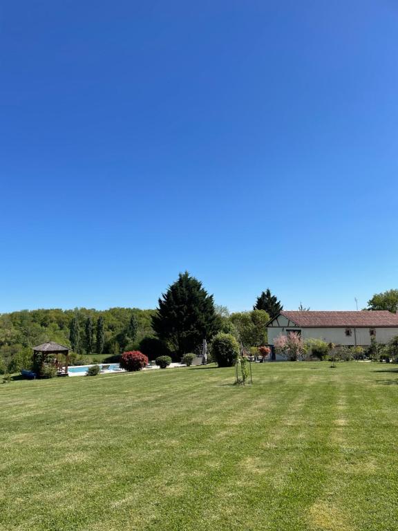 une grande pelouse avec une maison en arrière-plan dans l'établissement les gîtes de la fabrique, à Villeneuve-de-Duras