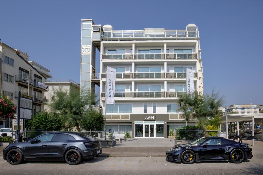 Dos coches aparcados delante de un edificio en Ambasciatori Suite Hotel, en Sottomarina