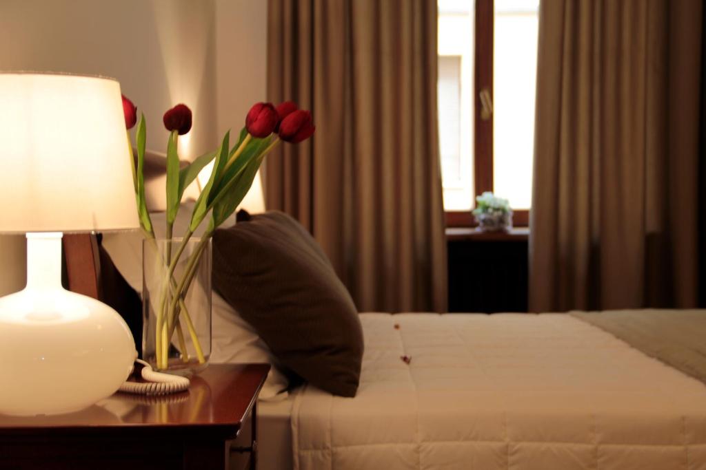 ローマにあるサンピエトロ　シックスルーム　&　スイートのテーブルに花瓶が飾られたベッドが備わる客室です。
