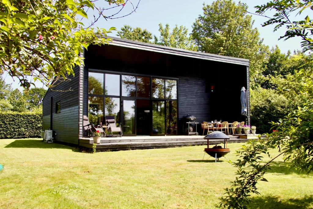 a black house in a garden with a lawn at Architect-Designed Holiday Home By Isefjord in Kirke-Hyllinge