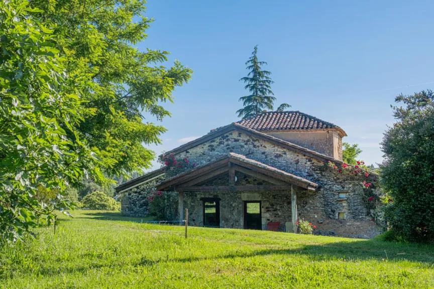 un vieux bâtiment en pierre avec une tour au sommet dans l'établissement Les Petites Écuries, à Gavaudun