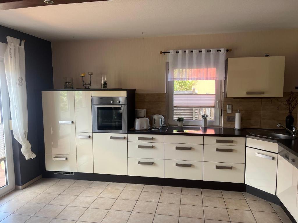 Una cocina con gabinetes blancos y un microondas. en Haus Brekersmeden, en Zingst