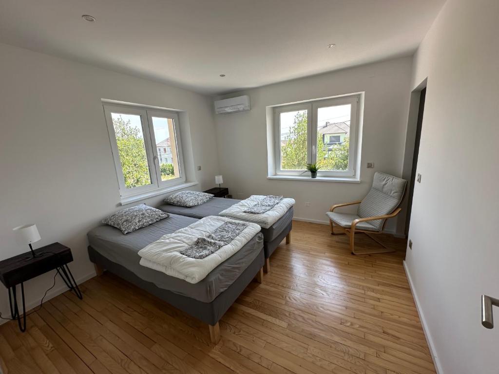 two beds in a room with two windows at Gite de la chapelle-Le hibou in Innenheim