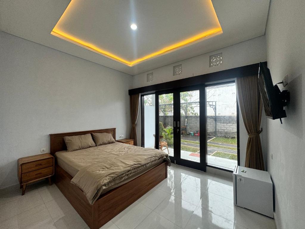 a bedroom with a bed and a large window at Kubu Taraya in Jimbaran