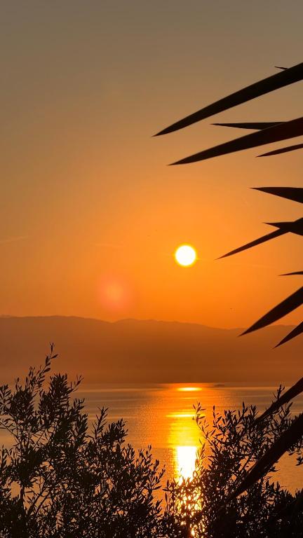 a sunset over the water with the sun in the sky at Nikoli Apartments in Benitses
