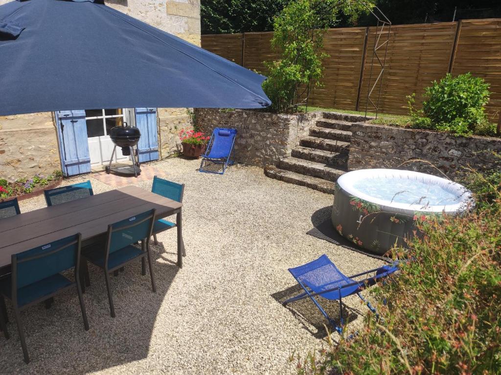- une table et des chaises avec un parasol et un foyer extérieur dans l'établissement Maison authentique du Vexin, à Théméricourt