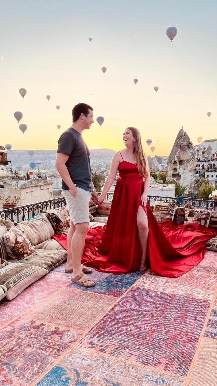 a man and a woman in a red dress standing on a roof at Caftan Cave Suites in Göreme