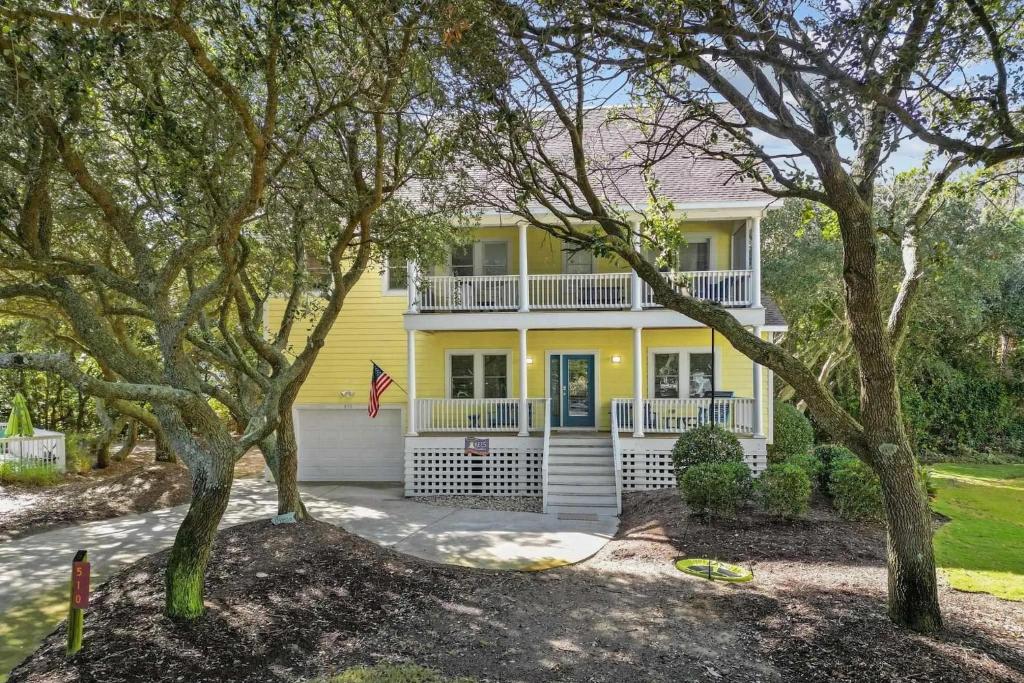 a yellow house with trees in front of it at Limoncello Grove Formerly Moondance in Corolla