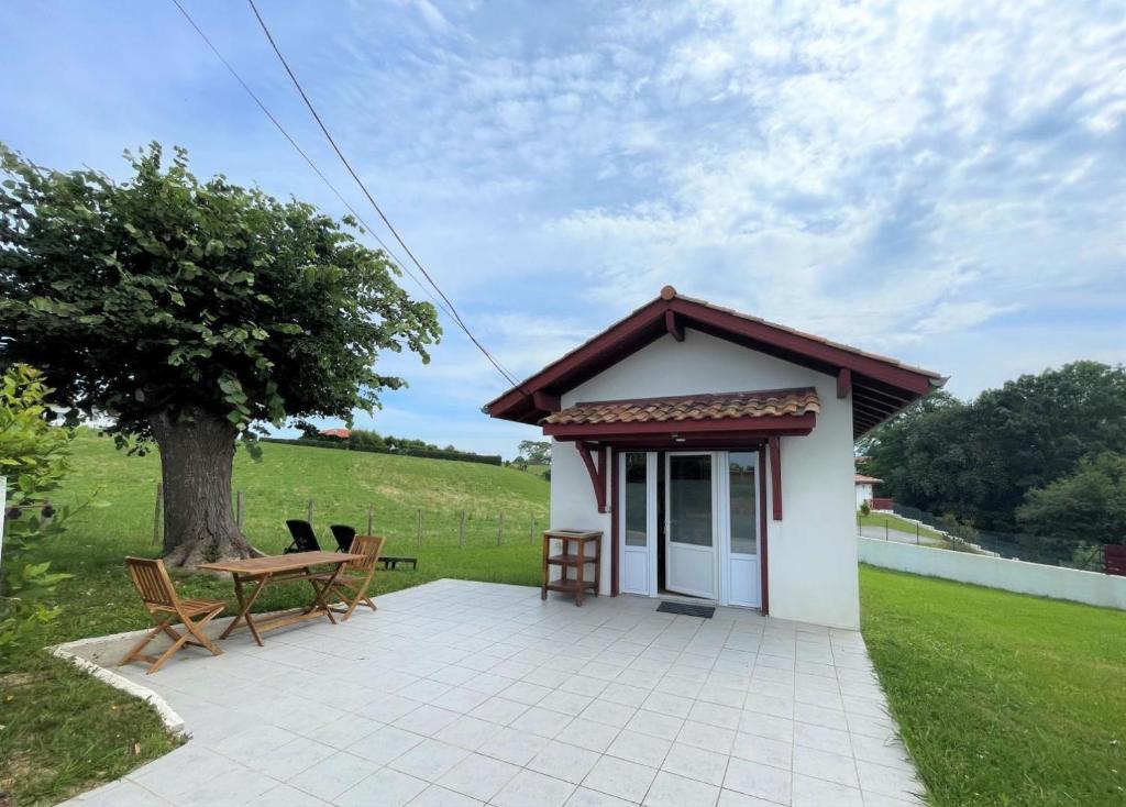a small house with a table and chairs and a tree at Etxe ttikia in Ahetze