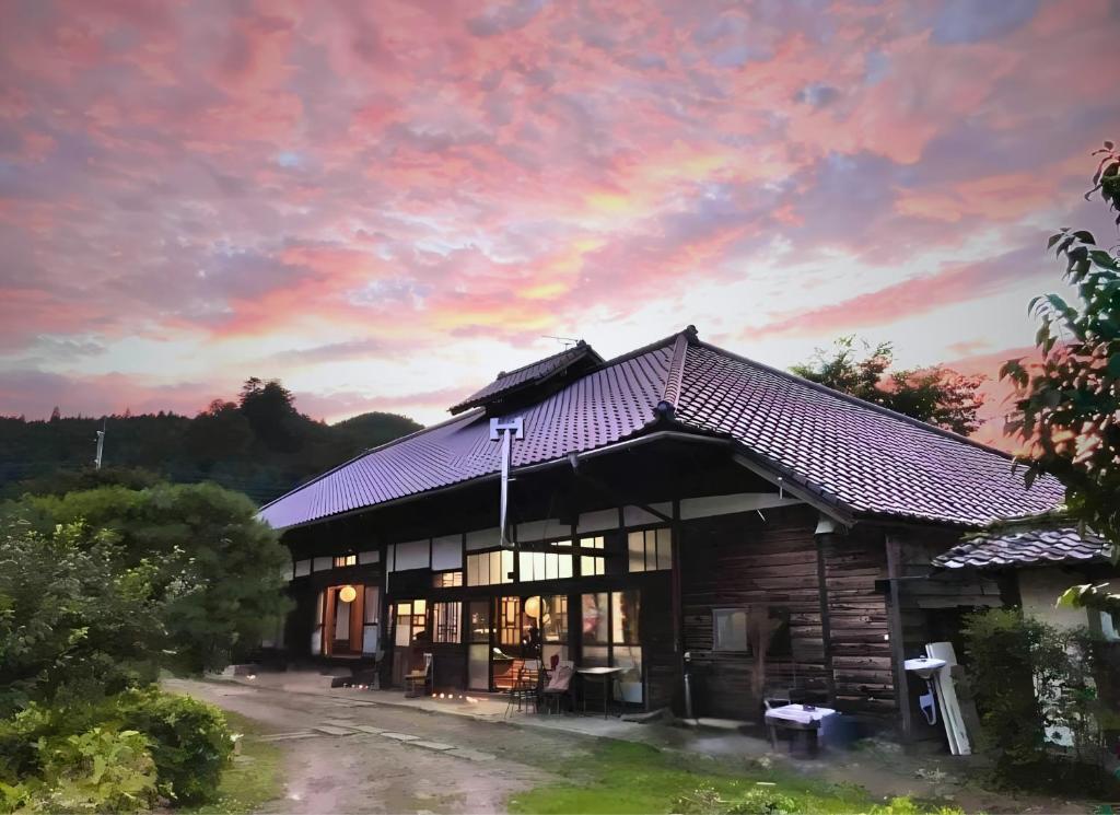 a house with a sunset in the background at THE Aramaki 日本の魅力と伝統が詰まった築200年の古民家 1日1組限定貸切 in Ō-naka