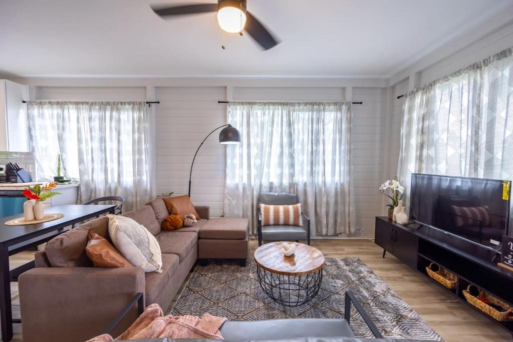 un salon avec un canapé et une télévision dans l'établissement Tropical Haven - 2BR Hilo, à Hilo