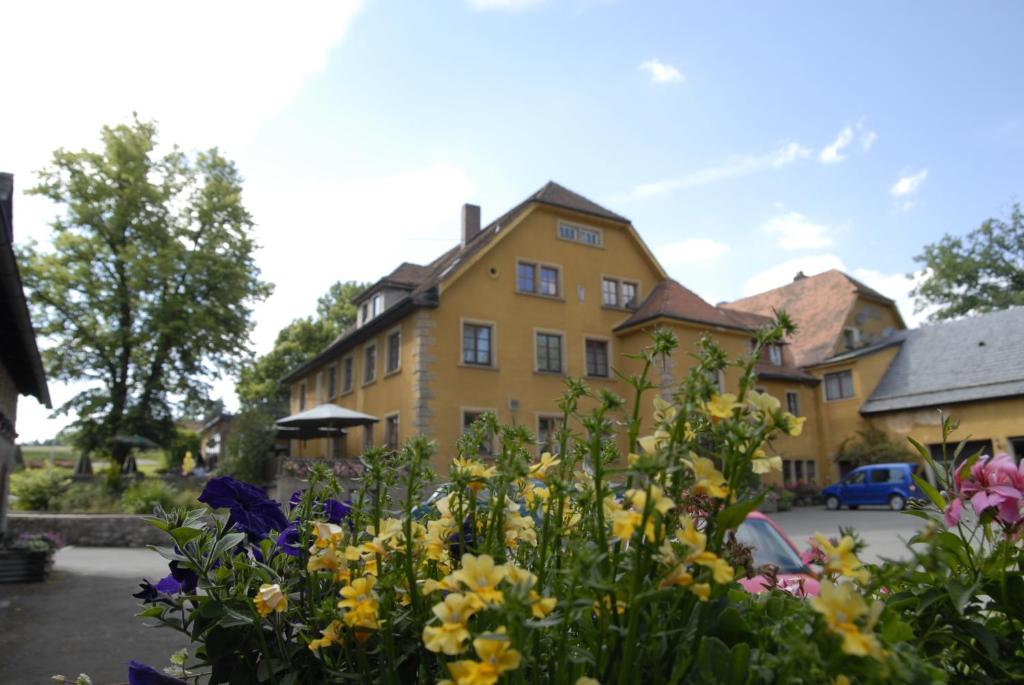 Landgasthof Haueis في Marktleugast: مبنى اصفر وامامه زهور