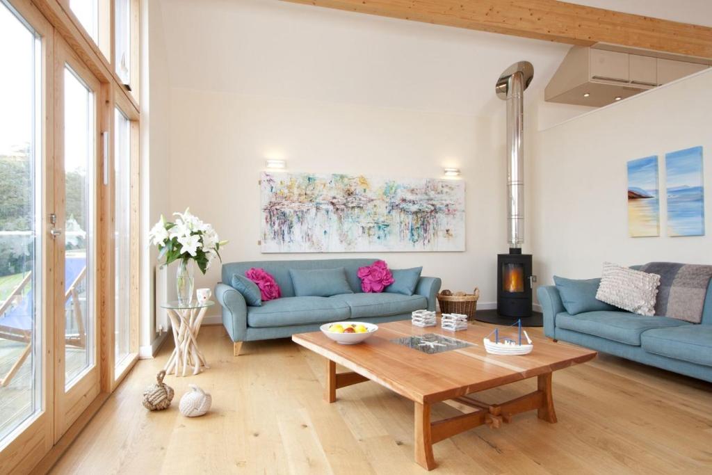 a living room with blue couches and a table at House 29 in Looe