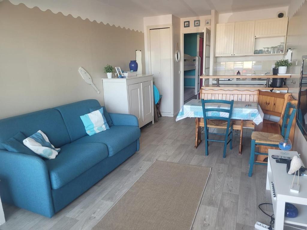 a living room with a blue couch and a kitchen at La BRIGANTINE 3 in Fort-Mahon-Plage