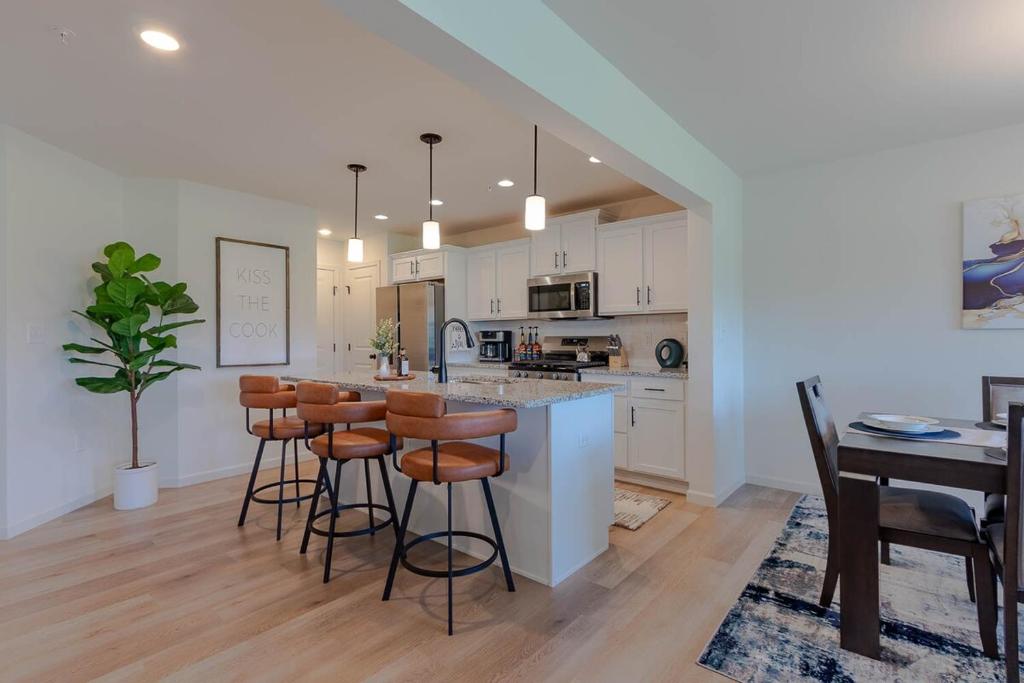 a kitchen with white cabinets and a bar with stools at The Cobbin Luxe, Luxe Stay Minutes from Penn State in State College
