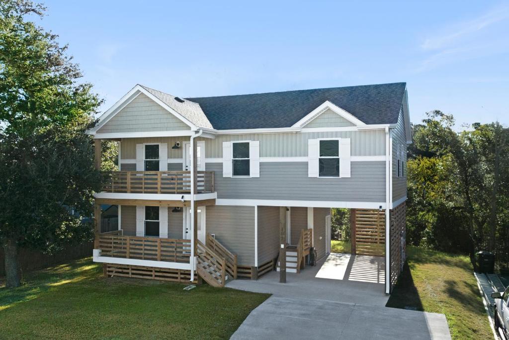 a white house with a porch and a yard at Masons Beach House Getaway in Kill Devil Hills
