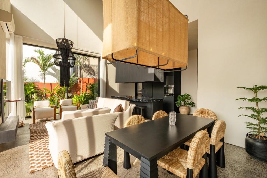 ein Esszimmer mit einem schwarzen Tisch und weißen Stühlen in der Unterkunft Five Stories Villas By SUOM in Canggu