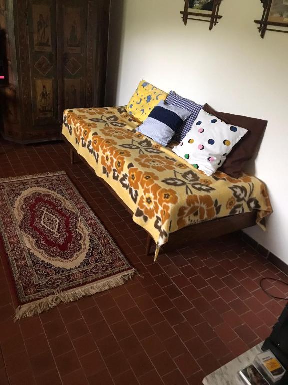 a bed with colorful pillows and a rug in a room at The House Next to the Forest - LAKMAT in Nové Hamry
