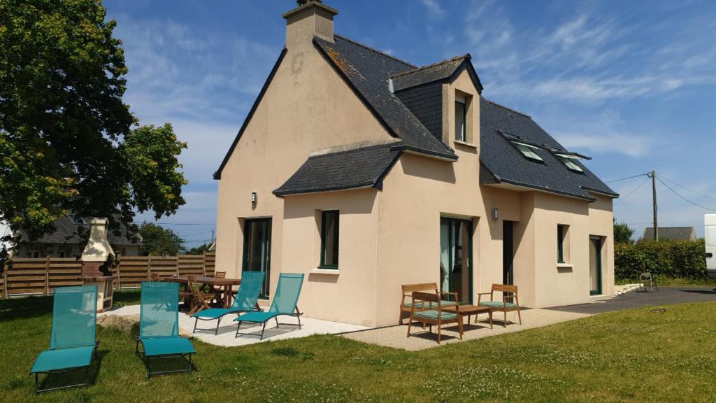 a building with chairs and tables in front of it at Maison de vacances - 6 à 8 personnes in Cléder