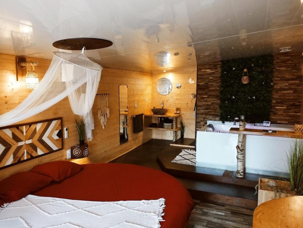 a bedroom with a red bed and a kitchen at L'Idylle Moment de Détente in Nay