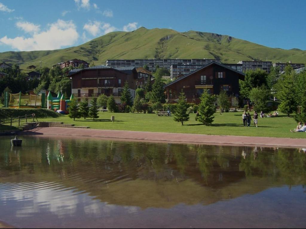 un bâtiment à côté d'un lac avec des montagnes en arrière-plan dans l'établissement Grand T3- pied des pistes-63 m2-8 personnes, à La Toussuire