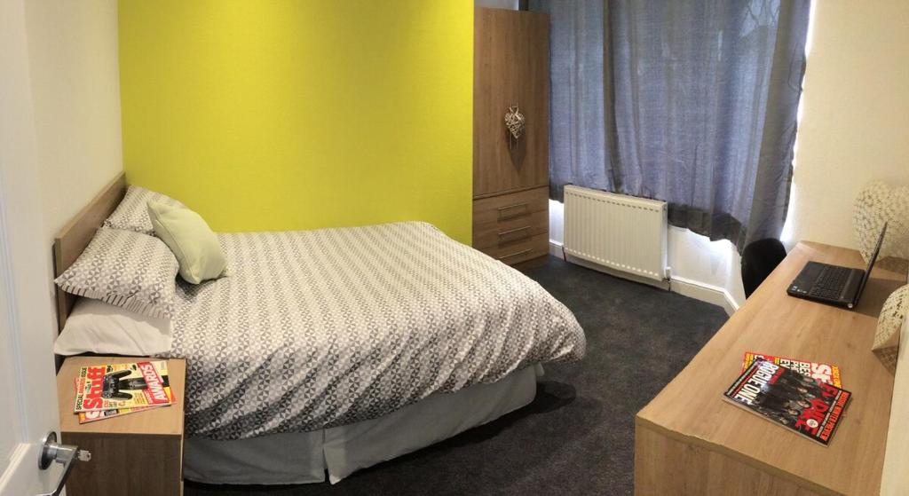 a bedroom with a bed and a yellow wall at Warm & Cozy 3-Bed Apartment at Kexgill in Middlesbrough